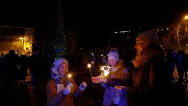 Katika mji mkuu wa Ukraine wa Kyiv, familia inakusanyika karibu na mti wa Krismasi kusherehekea mwaka mpya kabla ya amri ya kutotoka nje, huku kukiwa na mashambulizi ya Urusi nchini humo.