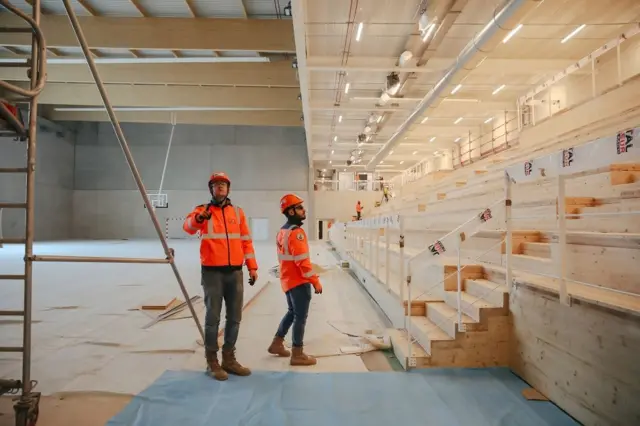 Dos trabajadores en un recinto deportivo en obras de construcción