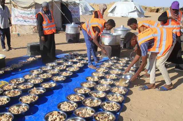 متطوعون سودانيون بإعداد وجبات مجانية للنازحين من مدينة الفاشر في مخيم العفاض للنازحين بمدينة الضبّة شمال السودان