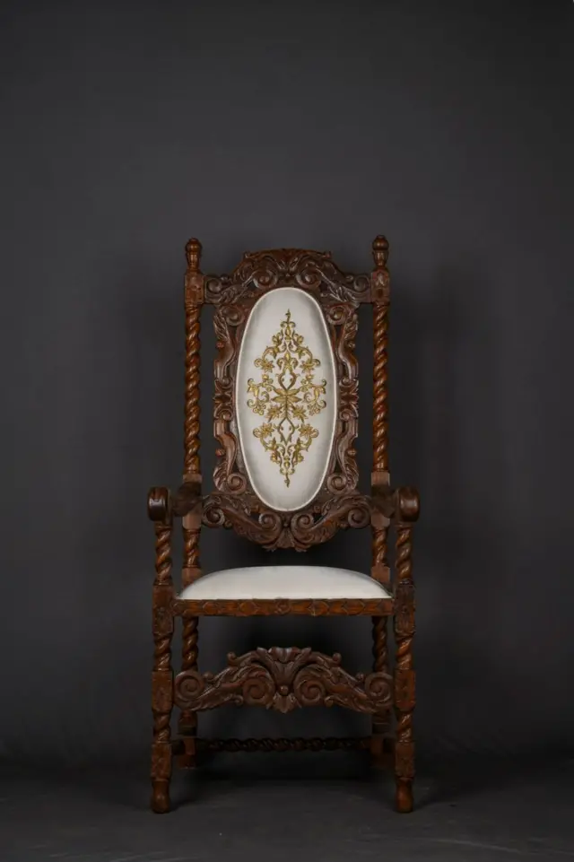 इंग्लंडमधील लोकप्रिय असलेली ही 17 व्या शतकातील 'कॅरोलियन' शैलीतील खुर्ची भारतातील एका जुन्या फर्निचरच्या दुकानात सापडली होती. बहुधा एखाद्या ब्रिटिश अधिकाऱ्याने ही वापरली असावी असा अंदाज आहे. या खुर्चीवर अतिशय बारीक कोरीव काम आणि सोन्याच्या धाग्यांनी केलेले भरतकाम पाहायला मिळते.