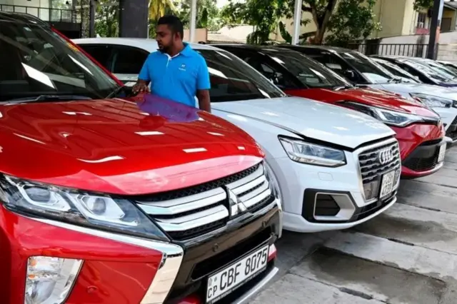 කොළඹ වාහන අලෙවි මධ්‍යස්ථානයක මෝටර් රථ අතර ඇවිද යන ශ්‍රී ලාංකිකයෙක්