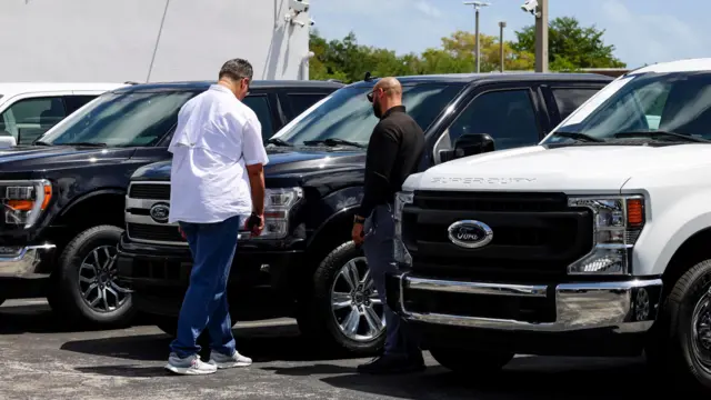 Двое мужчик рассматривают гигантские машины на парковке автосалона в Майами