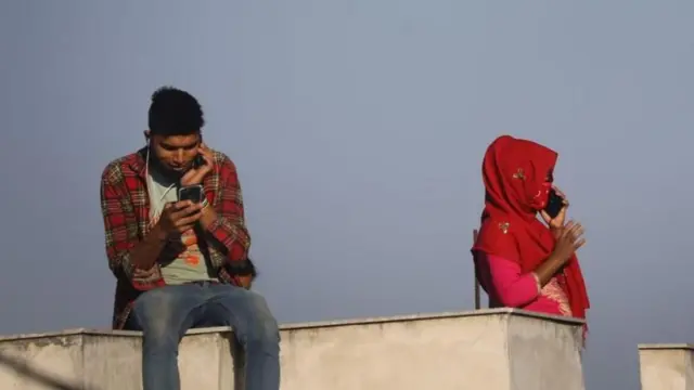 फोन चलाउँदै दुई व्यक्ति