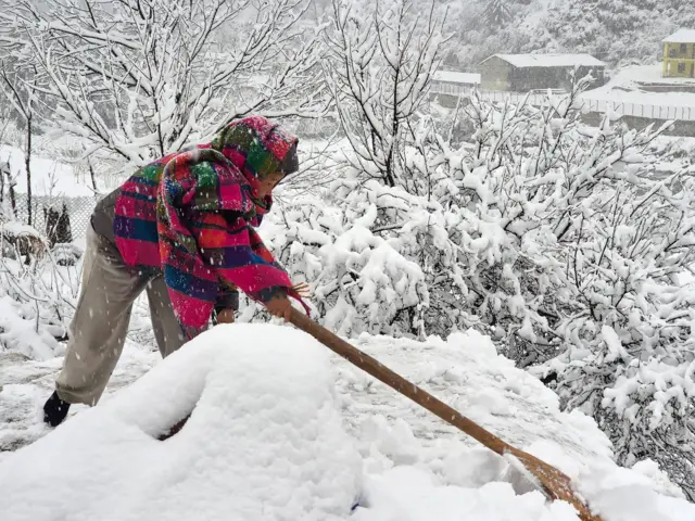 डोल्पाको जगदुल्लास्थित काइगाउँमा हिउँ पन्छाउँदै एक महिला 