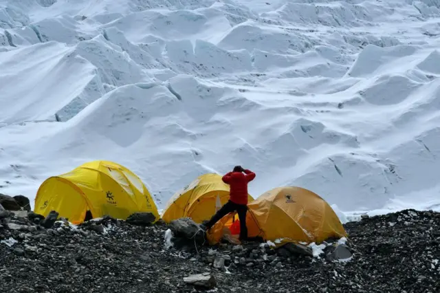 सगरमाथाको आधार शिविरबाट दुरबिनले खुम्बु आइसफलतिर हेर्दै एक पर्यटक