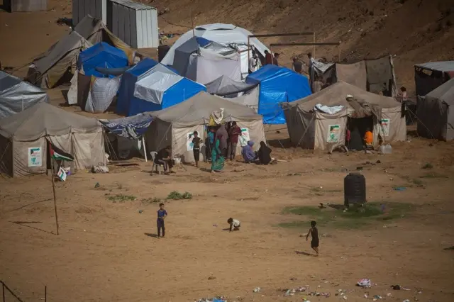 Niños y familias en un terreno donde hay tiendas de campaña
