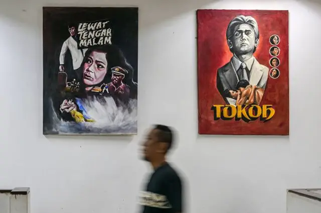 Seorang pria berjalan melewati beberapa poster film horor berjudul 'Past Midnight' di Pusat Film Usmar Ismail di Jakarta pada 11 April 2025. 
