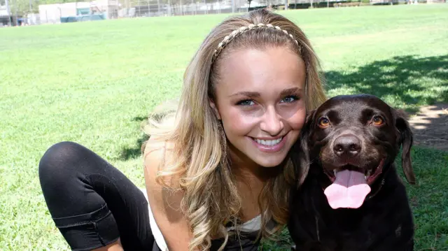 Hayden Panettiere, usando uma faixa na cabeça e sorrindo, posa para um retrato com seu cachorro em 2006.