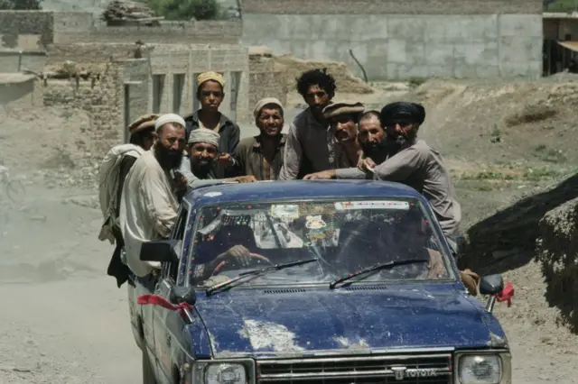 اگست 1988 میں جنگ سے بچ کر نکلنے والے افغان پناہ گزین پاکستان کے شہر پشاور میں واقع ایک کیمپ میں پک اَپ گاڑی کے ذریعے سفر کرتے ہوئے