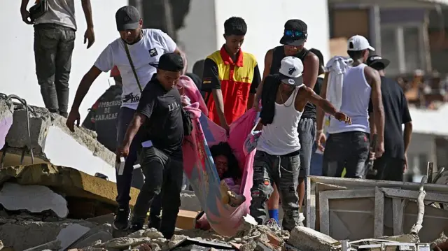 Un grupo de personas traslada a una mujer en una manta entre los escombros de un edificio de apartamentos dañado tras un terremoto en Catia La Mar, estado de La Guaira, Venezuela.