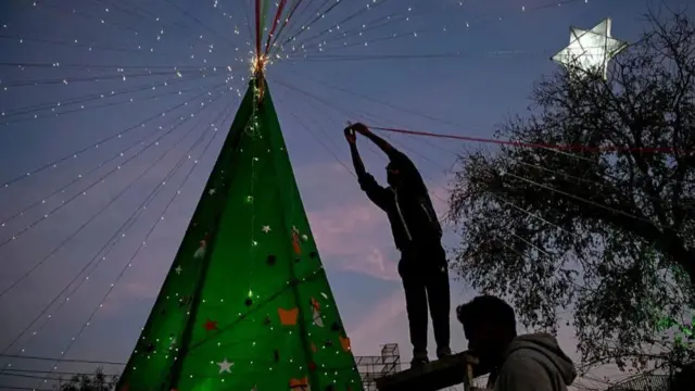 One man dey decorate Christmas tree during Christmas Eve celebrations for Islamabad, Pakistan