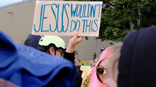 Manifestante segura um cartaz com os dizeres "Jesus não faria isso" em inglês, durante um protesto no lado de fora do centro de detenção do Serviço de Imigração e Alfândega dos Estados Unidos em Broadview, no Estado de Illinois, durante a mais recente batida contra imigrantes no país, no dia 10 de outubro de 2025