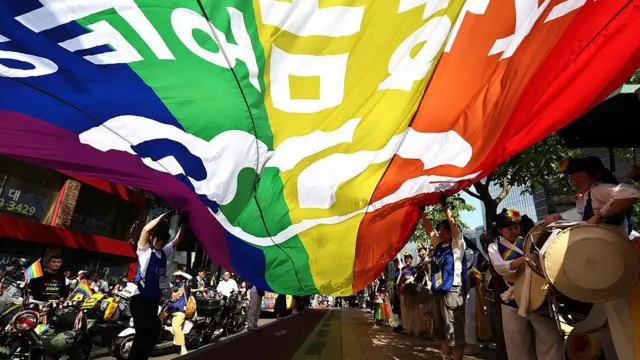 Apoiadores da comunidade LGBTQ desfilam com uma bandeira do arco-íris durante o Festival de Cultura Queer de Seul em 14 de junho de 2025 em Seul, na Coreia do Sul