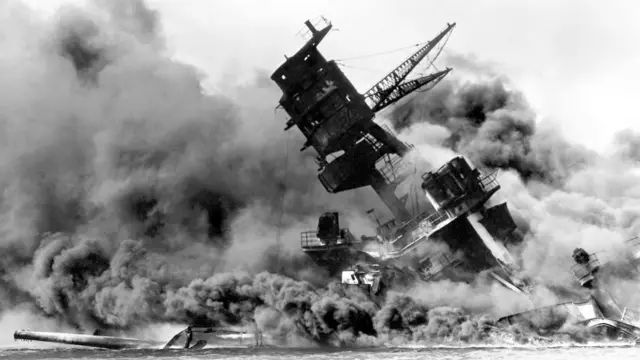 米戦艦アリゾナの白黒写真。船体が大きく傾き、巨大な煙に包まれている