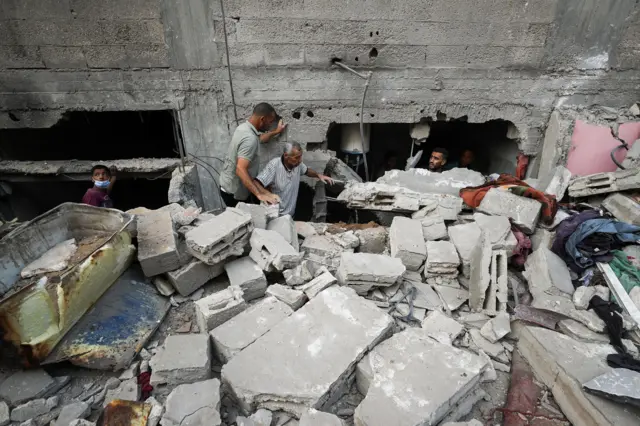 فلسطينيون يبحثون عن ضحايا في موقع غارة إسرائيلية ليلية على منزل في مدينة غزة، 6 يوليو/تموز 2025.