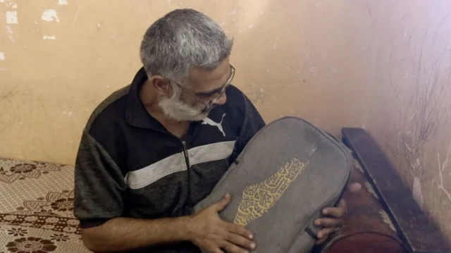 ضياء وهو يحمل بين بيديه حقيبة ابنه المدرسية