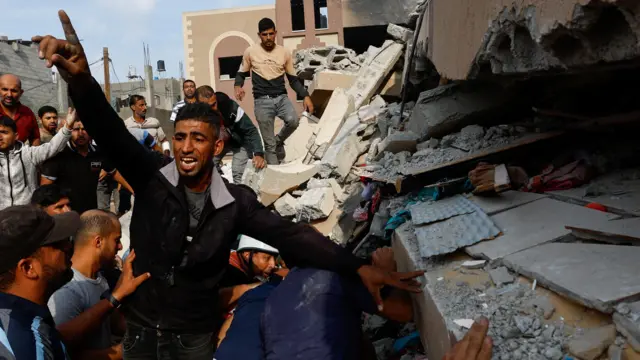 Warga Palestina mencari korban di antara puing-puing rumah yang hancur akibat serangan balik Israel di Khan Younis, di Jalur Gaza selatan pada Minggu (8/10/2023)