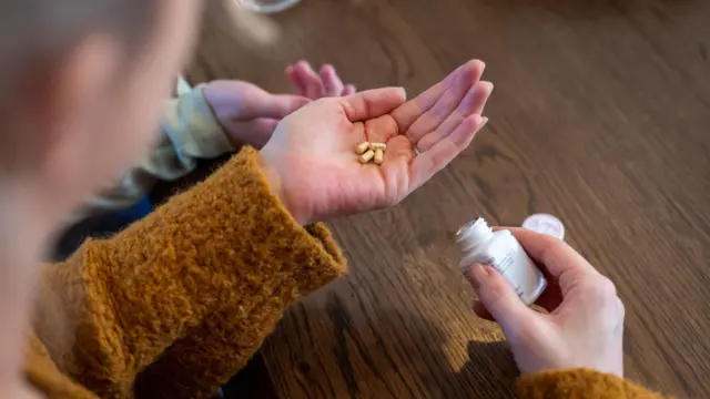 بزرگسالی (با چهره‌ای محو) در حال گرفتن قرص‌ها در مقابل یک کودک برای خوردن است