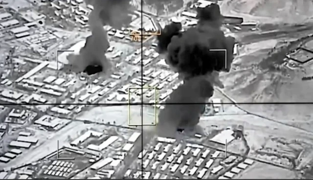 Siyah beyaz fotoğrafta yerleşim yerlerinden duman çıktığı görülüyor