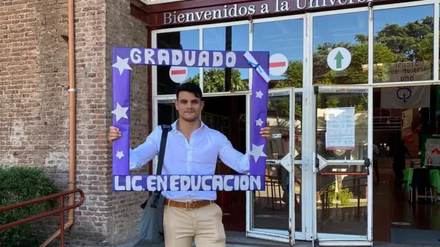 Leonel Ayala com um cartaz dizendo "Formado Licenciatura em Educação", em espanhol