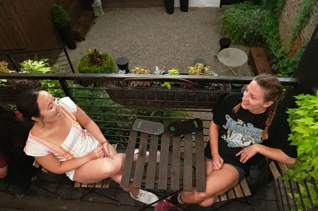 Duas mulheres jovens sentadas de frente para a outra e conversando