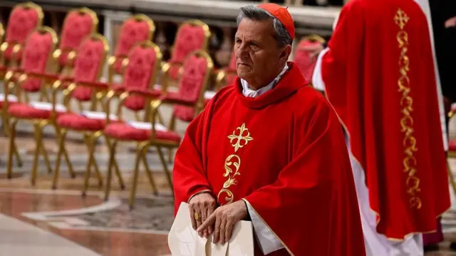 Cardinal Mario Grech, wearing a red cloak and holding his mitre in his hands, attends a mass at St Peter's basilica