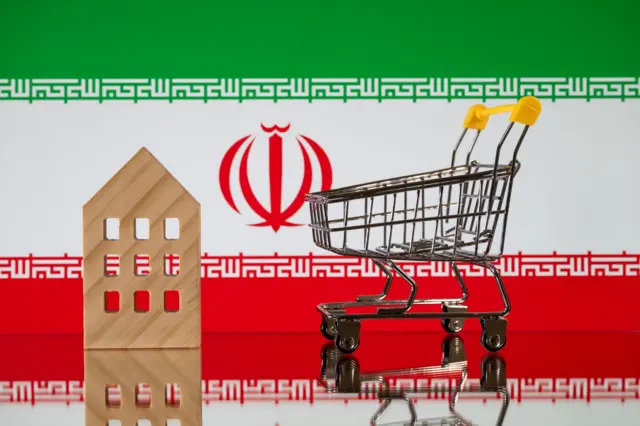 یک سبد چرخ‌دار خرید که خالی است، یک ساختمان شماتیک و پسزمینه پرچم ایران