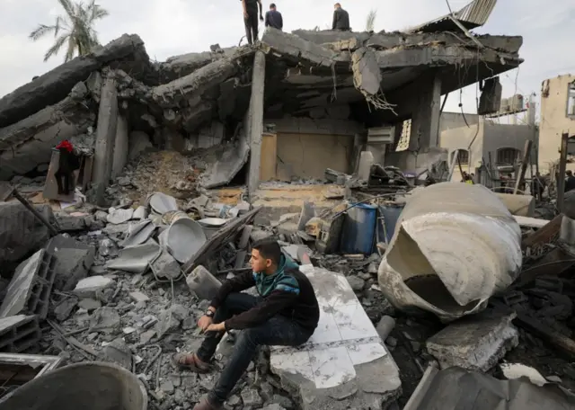فلسطينيون يتفقدون منزلا مدمرا في دير البلح، وسط قطاع غزة