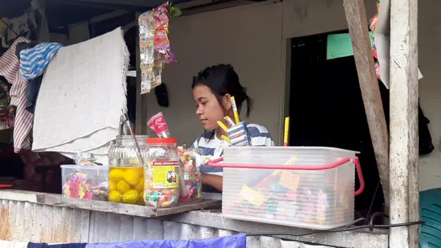 Astria menjual cemilan untuk anak-anak hingga manisan kedodong di depan rumahnya. 