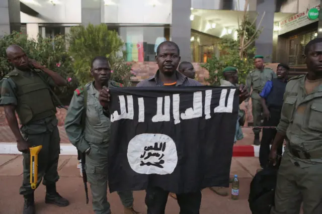 Des soldats maliens montrent le drapeau du groupe djihadiste, JNIM après l'attaque de Radisson Blu à Bamako.