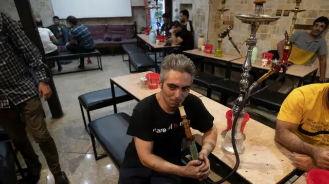 یک مرد ایرانی در حال قلیان کشیدن در یک چایخانه سنتی در جنوب تهران در تاریخ ۲۵ مرداد ۱۴۰۳ است.