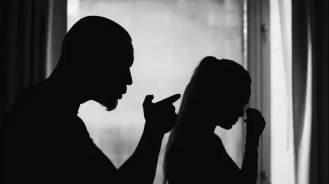 একজন পুরুষ এক হাত তুলে আঙুল তাক করে এক নারীকে ধমকাচ্ছেন