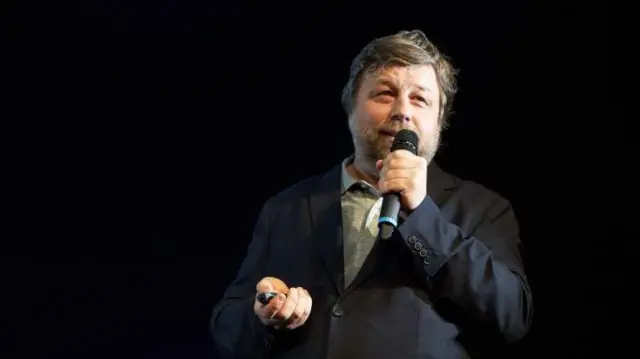 Чоловік у темному костюмі з мікрофоном