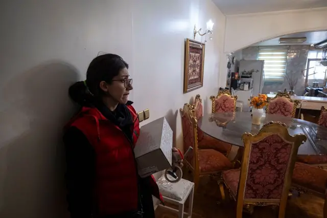 زنی در خانه نگران به دیوار تکیه داده است