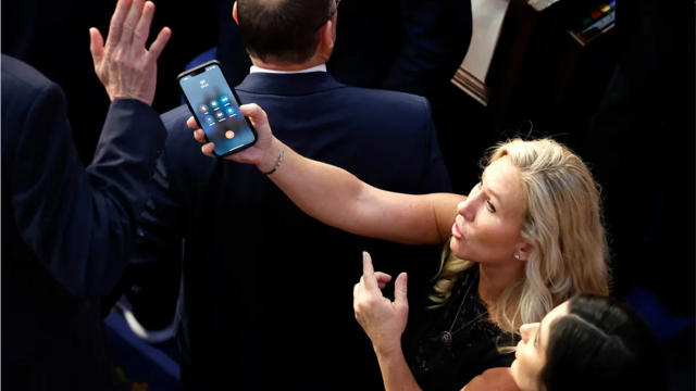 Marjorie Taylor Greene segura um telefone com Donald Trumploteriaonlineespera 