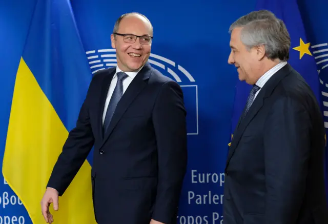 Усміхнений Парубій на тлі українського прапора та блакитного стенду з логотипом Європарламенту. Поруч стоїть у профіль Таяні