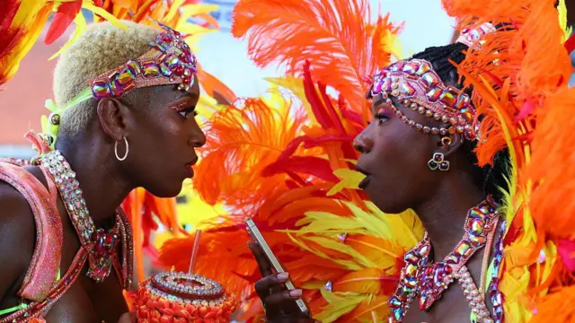 Две женщины в карнавальных костюмах, одна держит в руке телефон