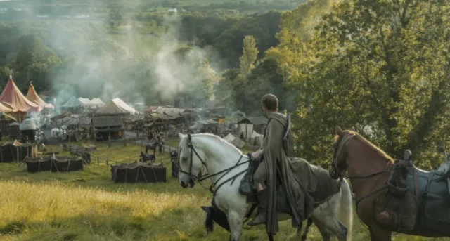 Beyaz ata binmiş şövalye, tepelik alandan çadırlı vadiye bakıyor.