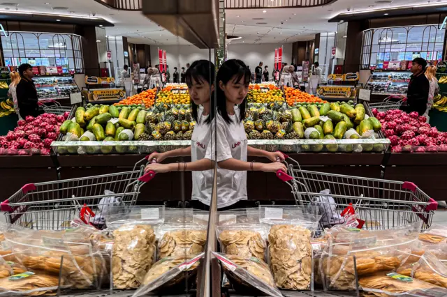 Seorang perempuan mendorong troli berisi kebutuhan pokok di salah satu pusat perbelanjaan di Semarang, Jawa Tengah, Minggu (12/04). 