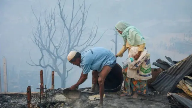 Duas pessoas recolhendo objetos e observando os estragos causado pelo incêndio