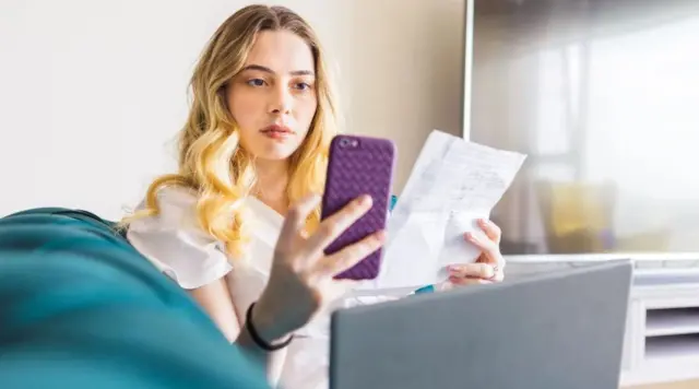 Смартфону менен чектерди текшерип отурган кыз