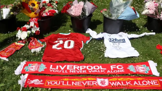 Camisetas y flores sobre el pasto frente al estadio de Anfield