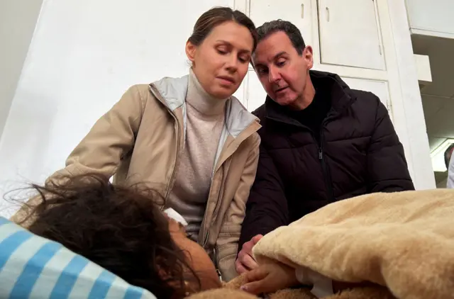 O ex-presidente sírio Bashar al-Assad ewww bet nacional comesposa Asma visitam uma sobrevivente do terremoto no Hospital Tishreenwww bet nacional comLatakia, Síria, após um terremoto. Eles são vistos olhando para uma menina quase totalmente coberta por um cobertorwww bet nacional comuma camawww bet nacional comhospital. Asma está vestindo uma jaqueta bege com uma gola rolê bege, enquanto Bashar al-Assad está com uma jaqueta preta sobre uma camiseta preta.