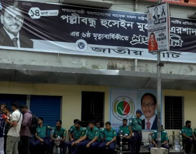 জাতীয় পার্টির অফিসের সামনে বসে আছে পুলিশ সদস্যরা, পাশে দাঁড়িয়ে আছেন কয়েকজন সাংবাদিক
