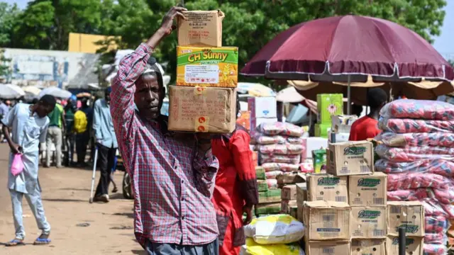 One man dey carry box of food for Niamey main market