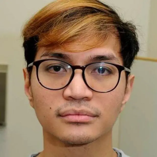 Foto Reynhard Sinaga mengenakan kacamata bingkai hitam dengan muka serius. Rambutnya dicat pirang.