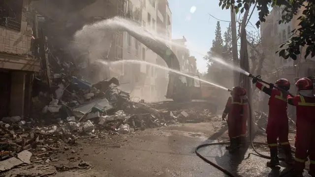 Petugas pemadam kebakaran memadamkan api di sebuah gedung yang hancur akibat serangan Israel pada 13 Juni 2025 di Teheran, Iran.