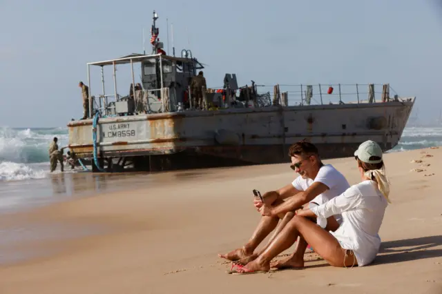 Dos bañistas miran una embarcación estadounidense encallada en la playa cerca de Asdod.