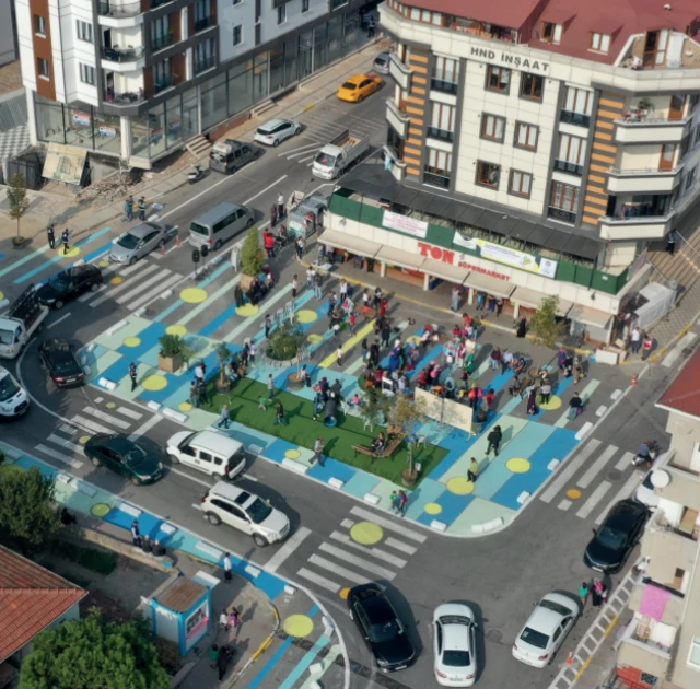 Şehirde bir kavşağın park ve oyun alanları ile tasarlandığı bir çizim. 