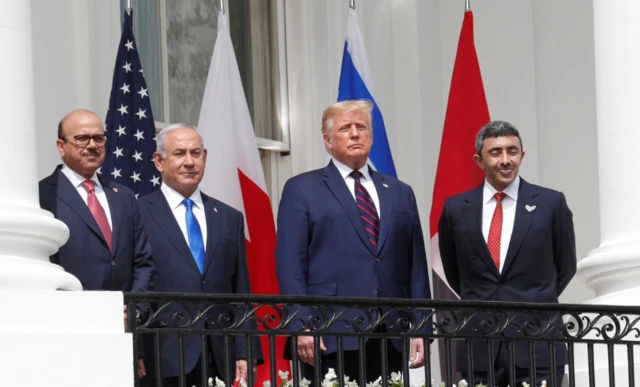 Beyaz Saray balkonunda Trump, Netanyahu ve iki Arap yönetici var. Hepsi takım elbiseli ve poz veriyorlar.